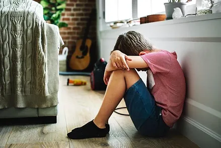 A young boy with his head on his knees