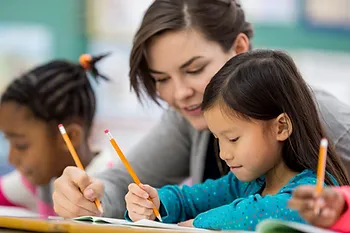 A teacher working with students to develop the mechanics of writing.